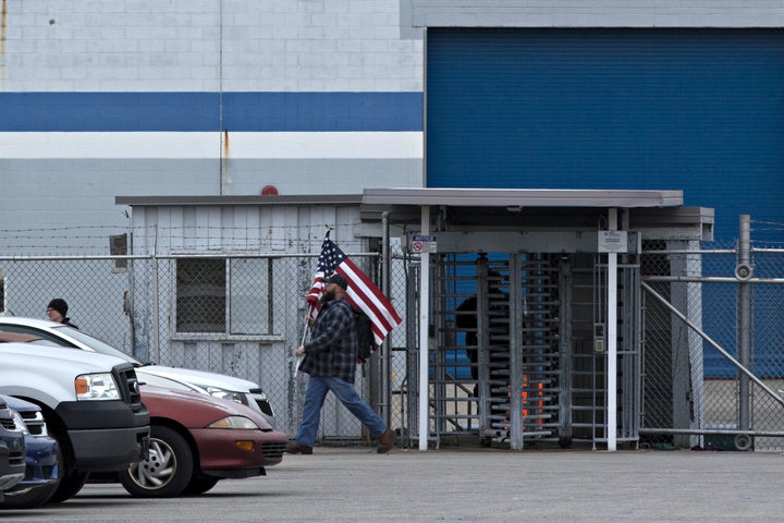 A man carries an American flag while leaving an employee entrance outside a Carrier facility in Indianapolis. 