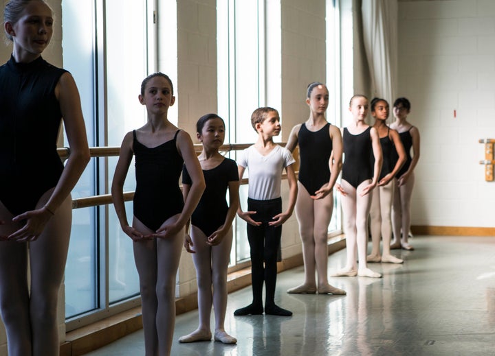 Boy and girl ballet dancers performing port de bras side stretches