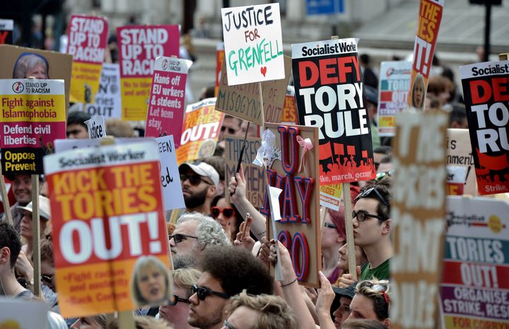 A demonstrator holds a placard reading 'Justice 4 Grenfell', relating to the June 14 fire at Grenfell Tower, during an anti-Conservative Party Leader and Britain's Prime Minister Theresa May, and Democratic Unionist Party (DUP) protest.
