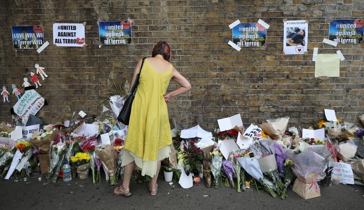 A woman looks at messages at the base of a wall near the scene of an attack next to Finsbury Park Mosque on June 20
