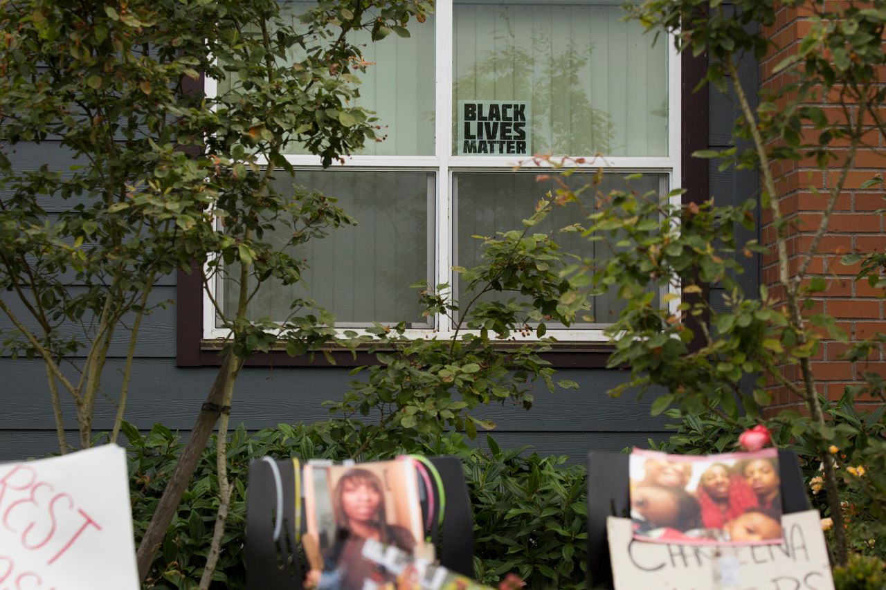 A Black Lives Matter sign sits in a window behind a memorial for Charleena Lyles at the Seattle apartment building where she was killed.