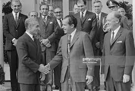 President Richard Nixon, with top advisors, welcomes the Shah of Iran, Mohammed Reza Pahlavi, to the White House. That is National Security Advisor Henry Kissinger, in glasses, above and between Nixon and Pahlavi.