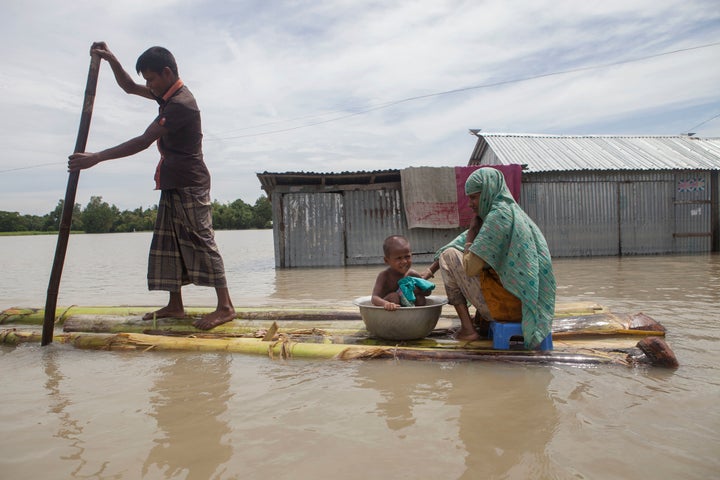 In this August 2016 photo, a family on a raft approaches a boat in a flooded area of Jamalpur, Bangladesh.