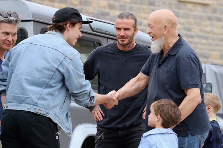 Brooklyn Beckham (2nd L) meets Glastonbury Festival founder Michael Eavis (R) with his father David Beckham (C)