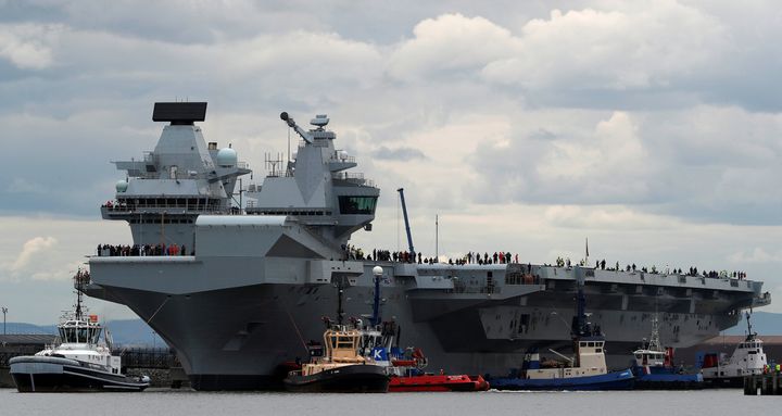 The British aircraft carrier HMS Queen Elizabeth is pulled from its berth by tugs before its maiden voyage, in Rosyth, Scotland