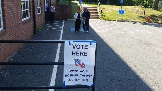 A “vote here” sign translated into Korean, Spanish and Vietnamese hangs near the entrance to a polling place set up in the Willston Community Center in Falls Church, Virginia. A growing number of communities are now required to translate election materials.