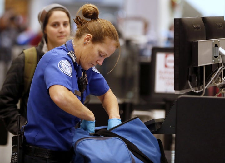 A TSA officer checks a traveler's bag at a screening location at Salt Lake City International Airport in Utah.