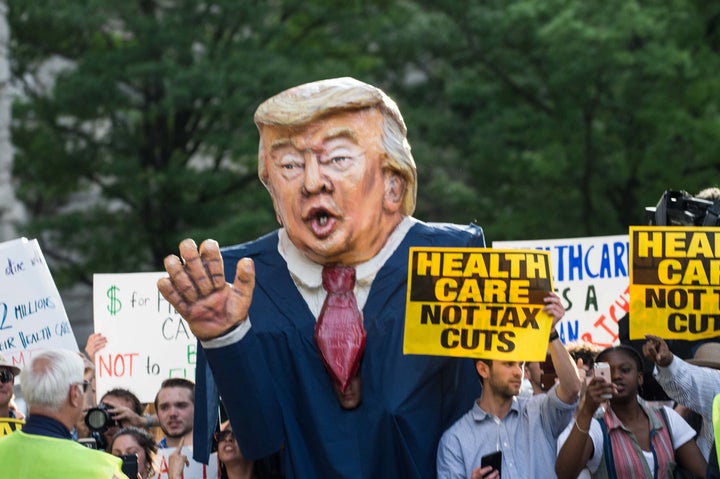 Protesters hold signs and an effigy of U.S. President Donald Trump as he arrives at the Trump International hotel.