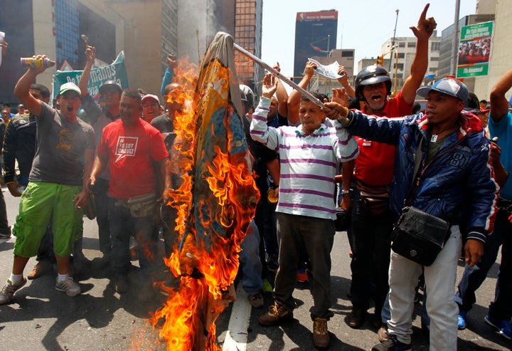 Supporters of the late President Hugo Chavez burn a flag with an opposition leader's campaign logo during a 2013 protest in Caracas. 