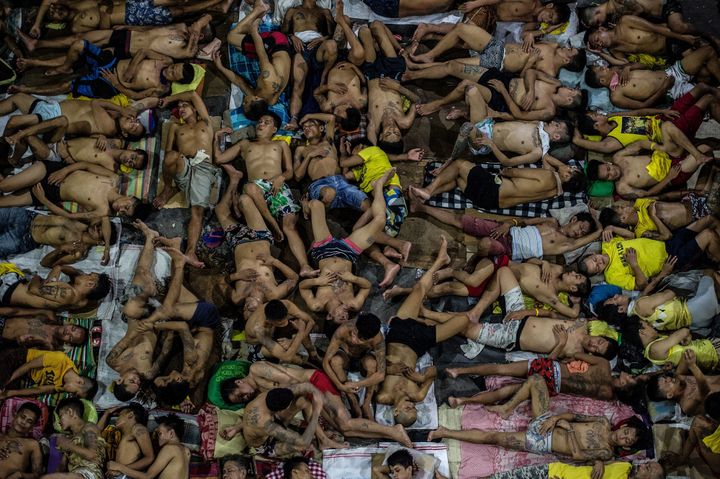 In this photo taken on July 19, 2016, inmates sleep on the ground of an open basketball court inside the Quezon City jail.