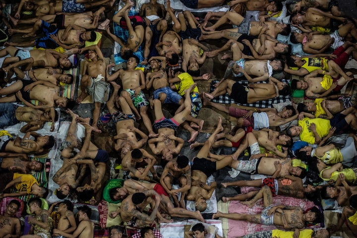 In this photo taken on July 19, 2016, inmates sleep on the ground of an open basketball court inside the Quezon City jail.