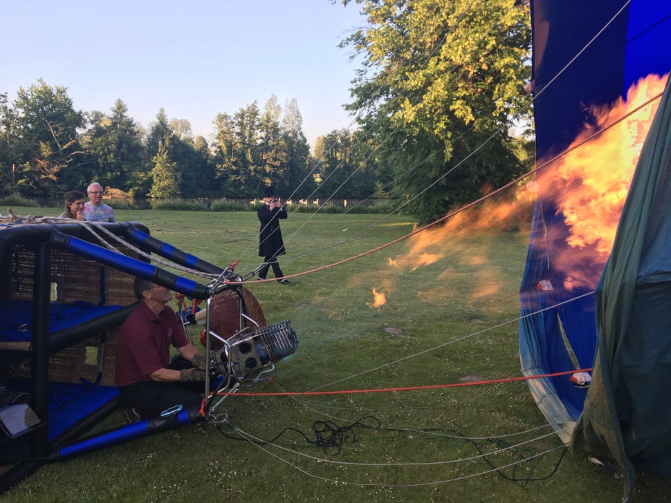 The balloon is filled with hot air on the ground and begins to rise as the air inside is less dense than the air outside.