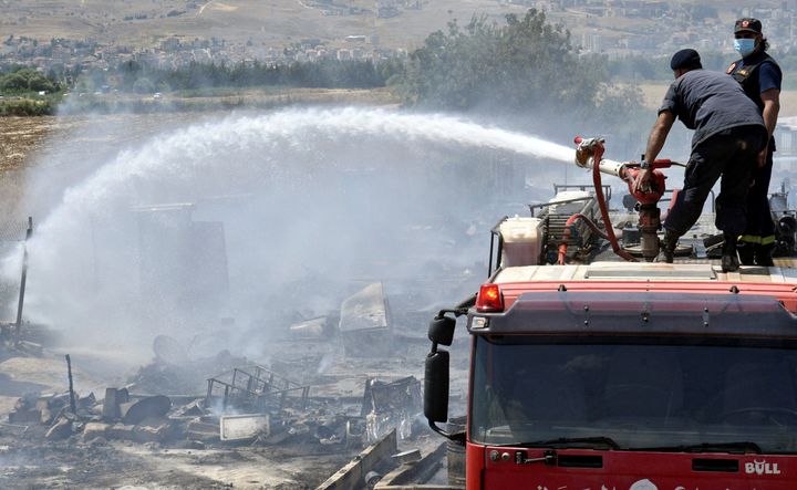 Civil defense members put out the fire in a camp near Qab Elias. 
