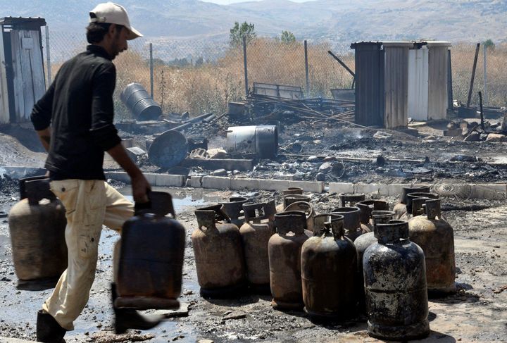 A man moves gas canisters after a fire tore through a camp for Syrian refugees. 