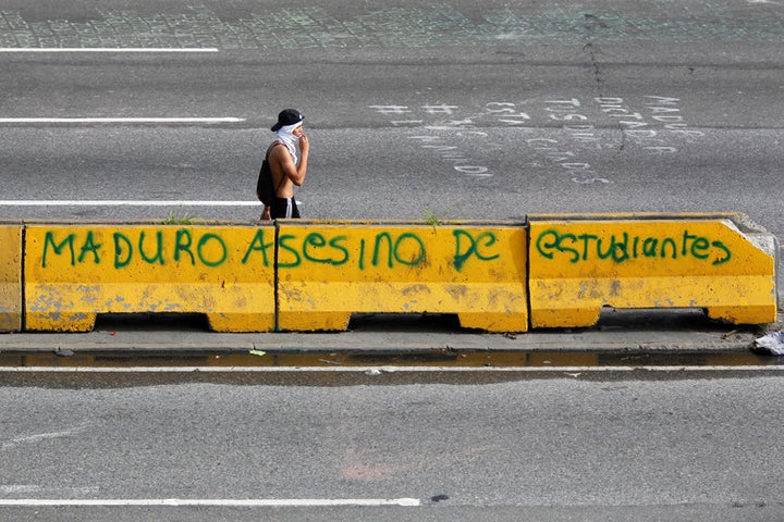 A protester passing grafitti that reads, ‘Maduro, murderer of students’.