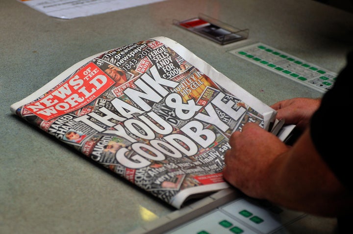 Printer Sean Leo reads the final edition of the News of the World newspaper as it rolls off the press in Hertfordshire