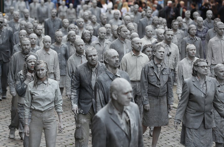 Performance artists covered in clay to look like zombies walk trance-like through the city center on July 5, 2017 in Hamburg, Germany.
