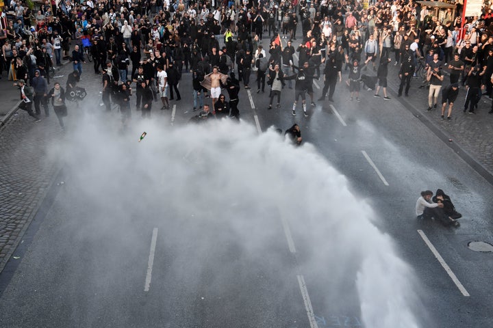 Protesters throw beer bottles as police use water cannon during the