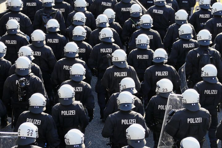 German riot police stand in front of protesters 