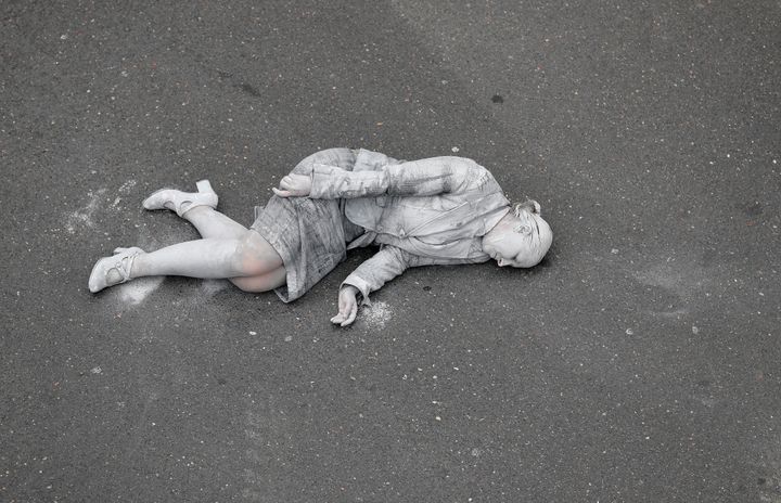 A woman painted grey lies on the ground as part of the performance 