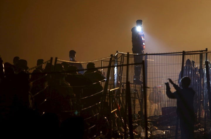 Austrian police guard migrants as they wait to cross the Slovenia-Austria border in Sentilj, Slovenia, October 2015.