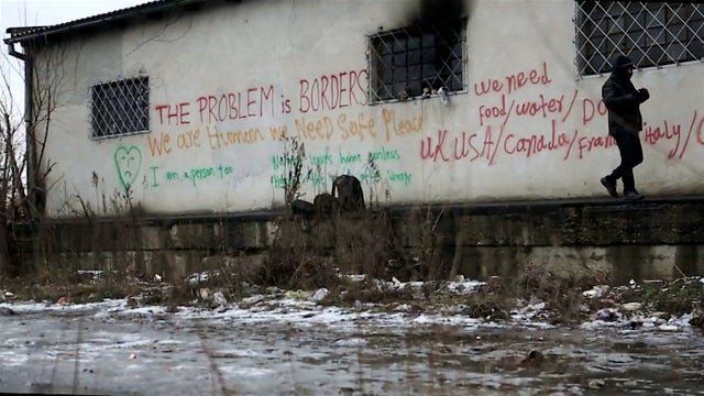 An asylum seeker walks past political graffiti at an abandoned warehouse close to Belgrade’s main train station.