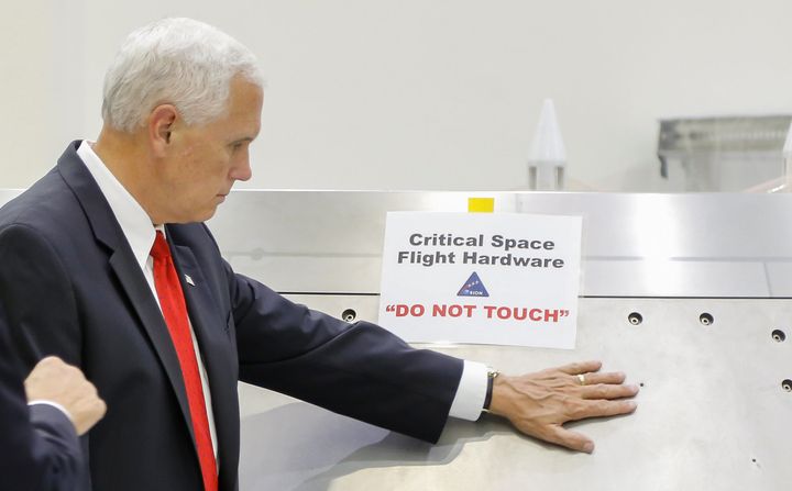 U.S. Vice President Mike Pence touches a piece of hardware with a warning label "Do Not Touch" during a tour of the Operations and Checkout Building in Florida on July 6, 2017.