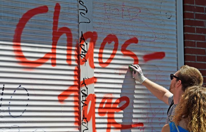 Residents clean a closed store, spray-painted with graffiti that reads "Hamburg chaos days."