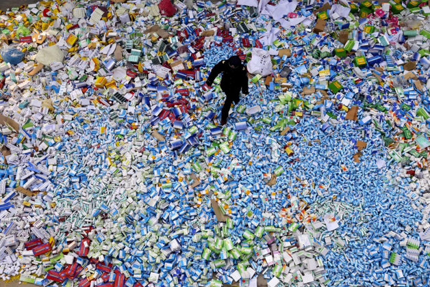 A Beijing policeman walks across a huge pile of fake medicines 