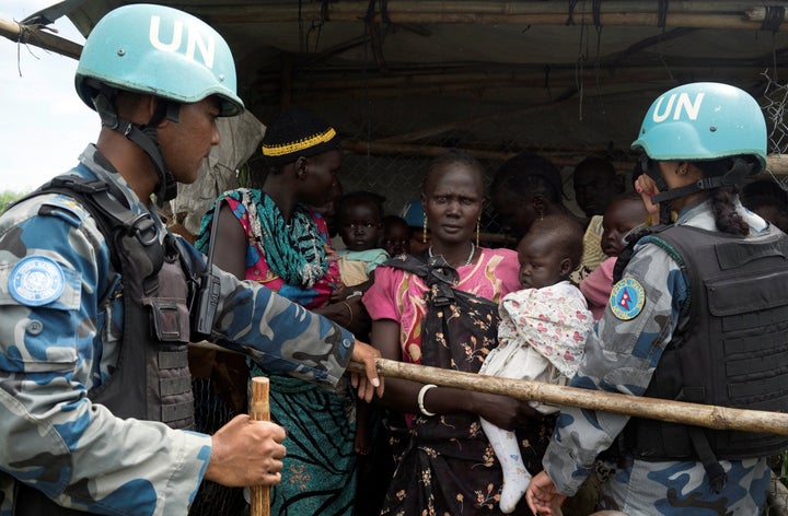 United Nations peacekeepers control South Sudanese women and children before the distribution of emergency food supplies in J