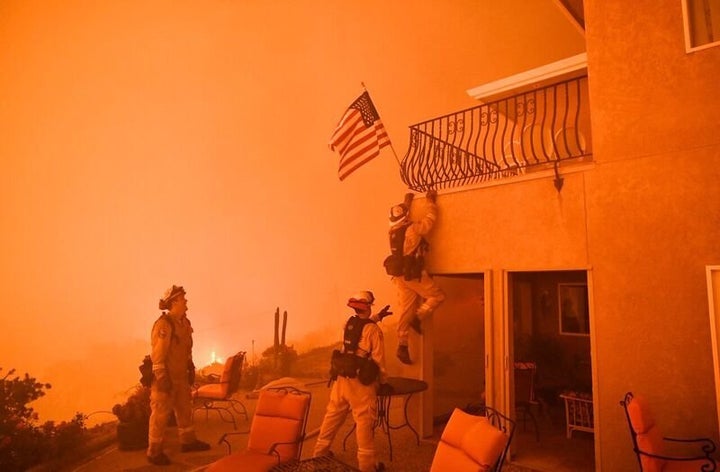 Firefighters save a US flag as impending flames from the Wall fire close in on a luxury home in Oroville, California on July 8, 2017.