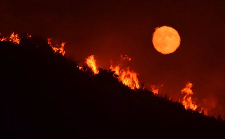 The full moon rises over flames of the Alamo fire in Santa Maria, California, on July 7.