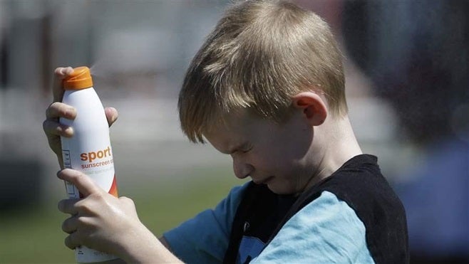 A boy sprays sunscreen in Scottsdale, Arizona. Arizona and several other states recently have enacted laws declaring that students may use sunscreen in school and at after-school activities without a doctor’s note.