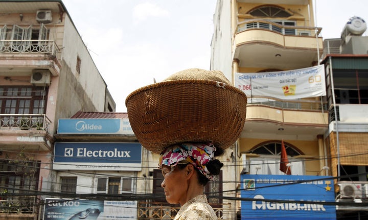  A woman carries a basket of bread for sale on her head on a street in Hanoi. 