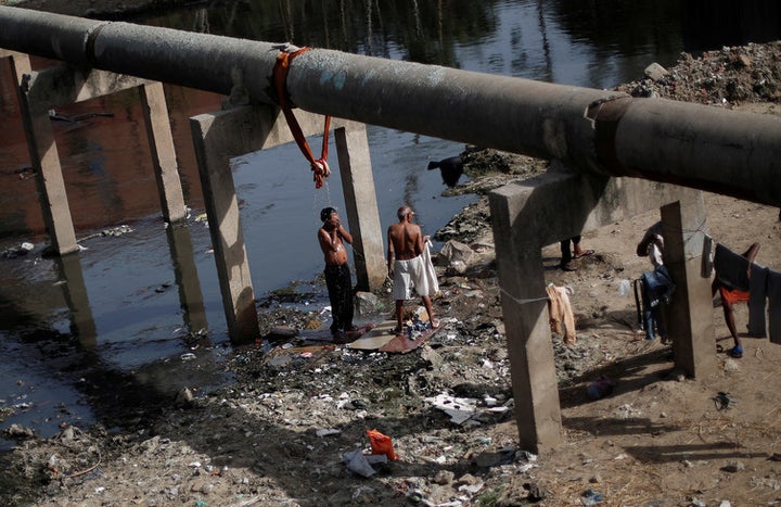 A man bathes under a broken water pipeline in New Delhi, India June 5, 2017.
