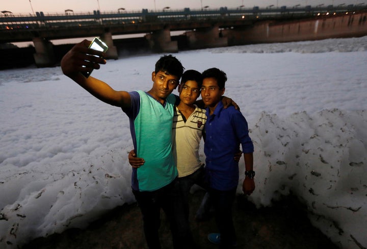 Boys pose for a selfie in front of the foam covering the polluted Yamuna river in New Delhi, November 2016.