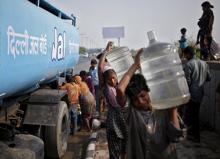 Slum dwellers carry filled water container from a tanker provided by the state-run Delhi Jal Board.
