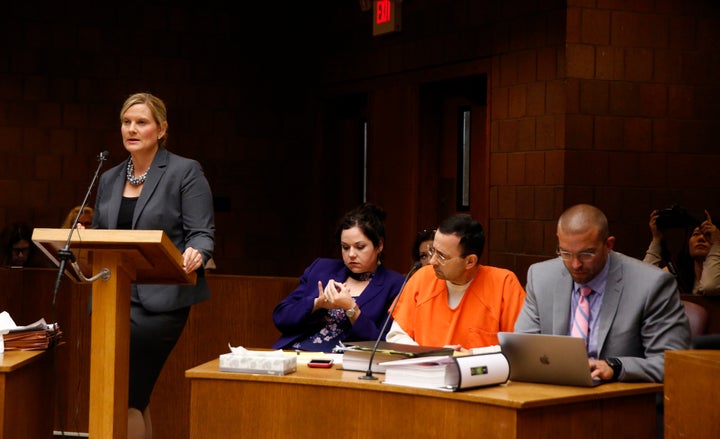 Asst. Michigan Attorney General Angela M. Povilaitis (L) speaks during a June 23 hearing of Larry Nassar. Defense attorneys Shannon Smith and Matt Newberg sit on either side of Nassar. 