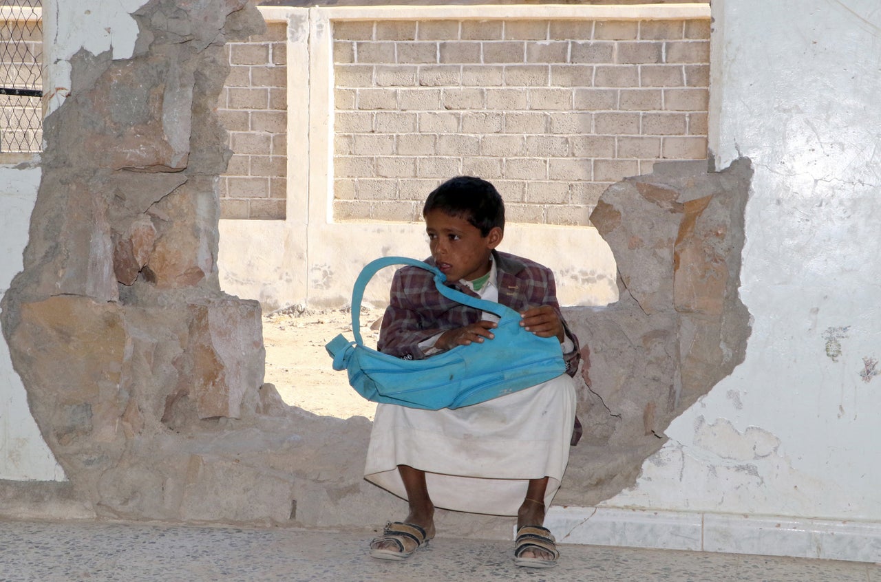 A boy sits in a hole in a school wall that was damaged in the ongoing conflict in Saada governorate on March 14, 2017.