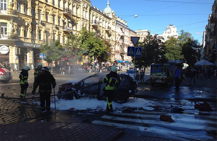 In this photograph taken by Olena Prytula before she realized her partner was in the explosion, firefighters douse the vehicle in a Kiev street. 