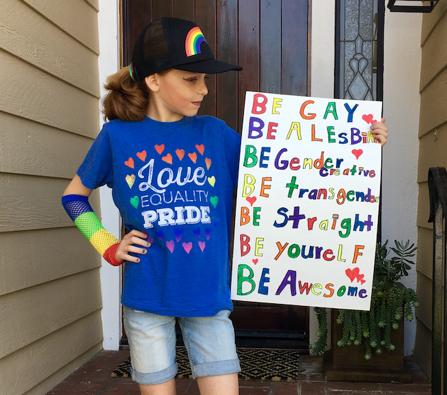 C.J. Duron posing with a sign he made for his city's local Pride festivities.