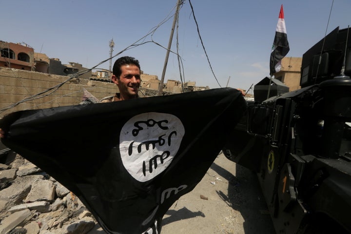 A member of Iraqi Counter Terrorism Service holds an Islamic State flag as he celebrates in the Old City of Mosul on Jul
