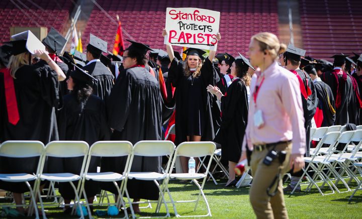 A woman carries a sign in solidarity for a Stanford rape victim during graduation at Stanford University on June 12, 2016. Stanford students protested the University's mishandling of rape cases, including the case of Brock Turner. 
