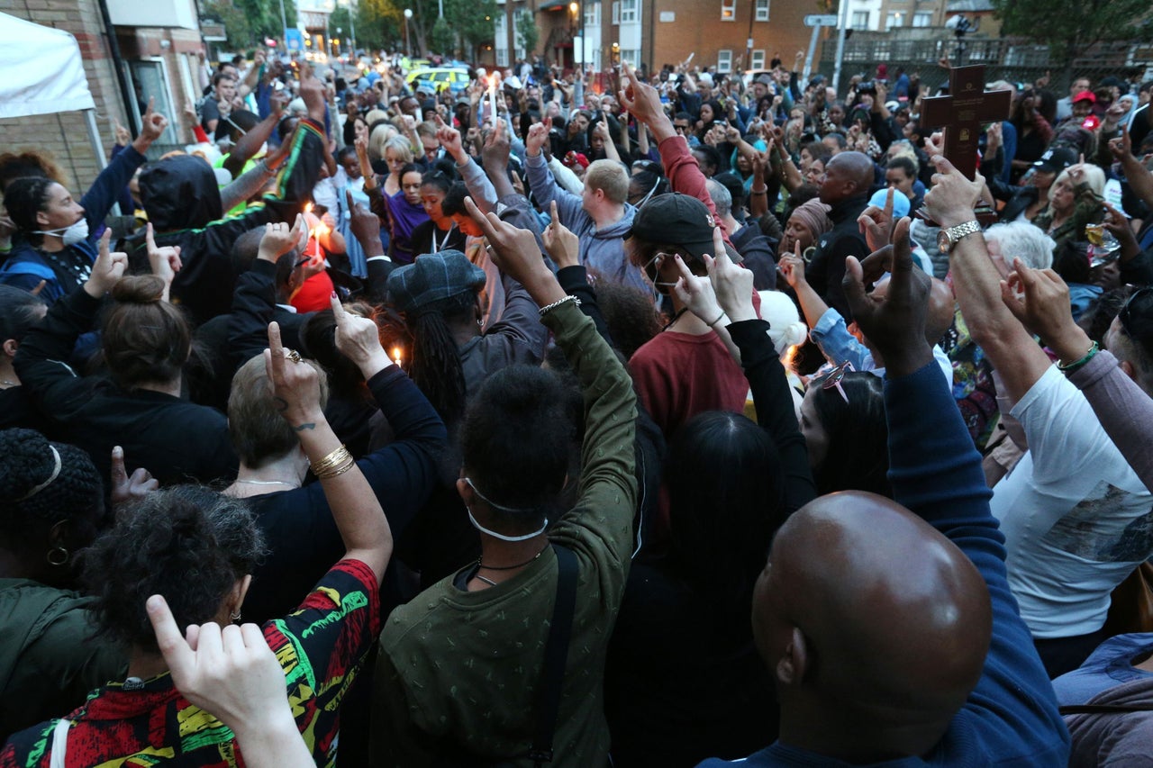 People attend a vigil to mark four weeks since the Grenfell Tower fire, at the memorial wall on Bramley Road, London.