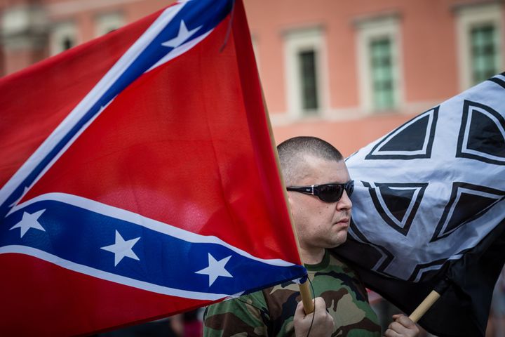 A far-right activist in Warsaw, Poland, holds a Confederate flag and a White Pride flag while taking part in a July 2015 demonstration against accepting over 2,000 immigrants to the country.