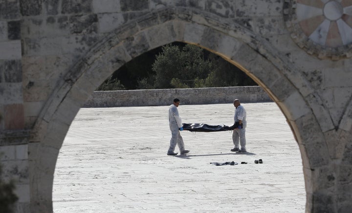 Israeli policemen carry the body of an assailant after he was shot dead by Israeli police at the compound known to Muslims as