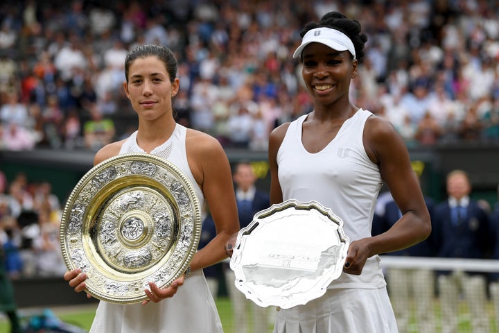 Garbine Muguruza of Spain celebrates victory with the trophy alongside runner up Venus Williams of The United States after the Ladies Singles final on day twelve of the Wimbledon Lawn Tennis Championships at the All England Lawn Tennis and Croquet Club at Wimbledon on July 15, 2017 in London, England. 