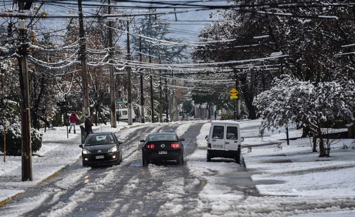 Cars drive along an icy street.