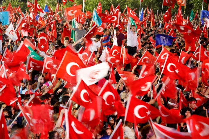 People wave Turkey's national flags as they attend a ceremony marking the first anniversary of the attempted coup in front of the Turkish Parliament in Ankara. 