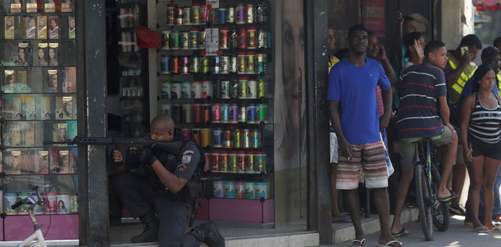 Police take aim at drug dealers in Rio’s City of God favela as locals look on.